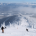 Skiers descend a snowy mountain slope at Schweitzer Mountain Resort, surrounded by snow-covered trees and distant hills under a clear blue sky, epitomizing the thrill found in every page of the Ski Season Guide.